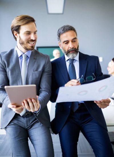 Mature businessman to discuss information with a younger colleague in a modern business lounge